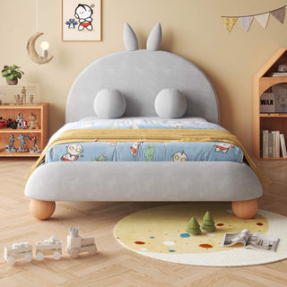 Children's bedroom with a gray bed featuring bunny ears, colorful bedding, and toys on the floor.