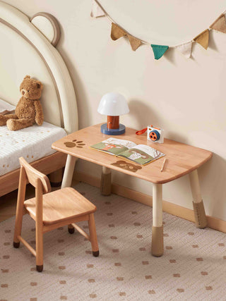 Children's wooden desk and chair set with toys and a teddy bear in a room.