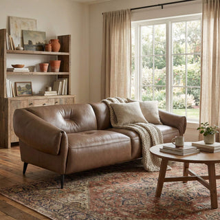 Cozy living room with a brown leather sofa, wooden coffee table, and large windows.