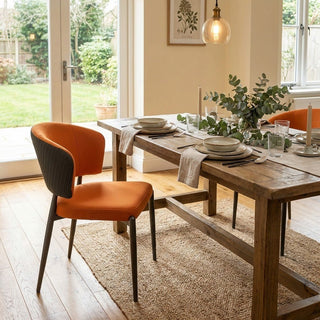 Dining room with wooden table and orange chairs, set for a meal.