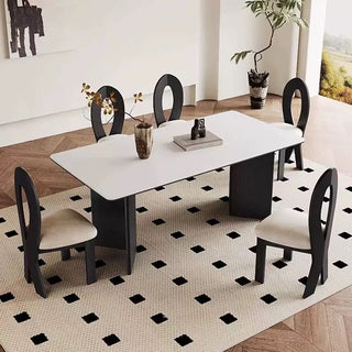 Dining table set with chairs in a room with a geometric patterned rug.