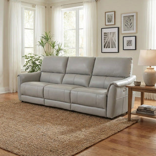 Grey sofa in a living room with a coffee table, lamp, and framed pictures on the wall.