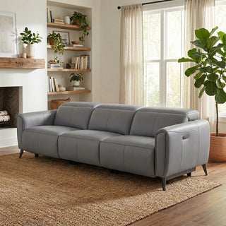 grey sofa in a living room with a fireplace, shelves, and plants.
