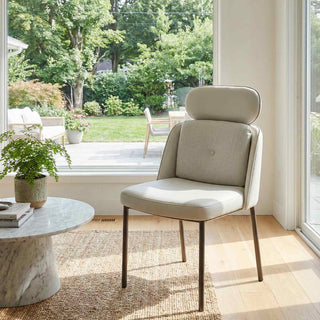 Modern beige chair in a bright room with large windows and outdoor view