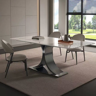 Modern dining table with chairs in a room with large windows.