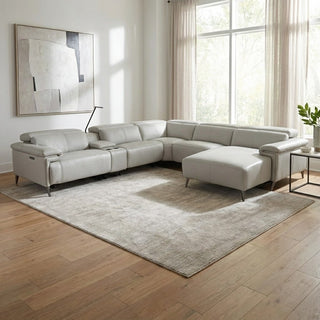 Modern living room with a white sectional sofa, large windows, and abstract art on the wall.