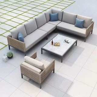 Outdoor patio furniture set with sectional sofa and coffee table on a tiled patio.