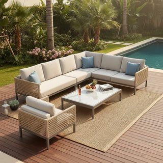 Outdoor patio set with sectional sofa, chairs, and coffee table on a wooden deck by a pool.