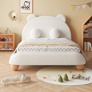 Children's room with a white teddy bear-shaped bed, toys on the floor, and shelves with books and figurines.