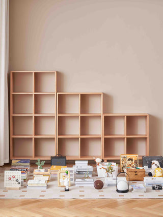 Wooden bookshelves against a beige wall with various decorative items on a wooden floor.