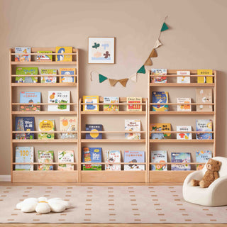 Wooden bookshelves filled with children's books in a room with a teddy bear and decorative items.