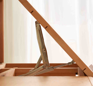 Wooden folding chair with metal hinges against a white curtain background