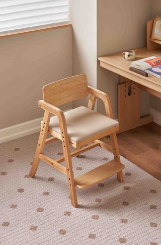 Wooden kids chair with a cushion on a patterned carpet in a room with a desk.