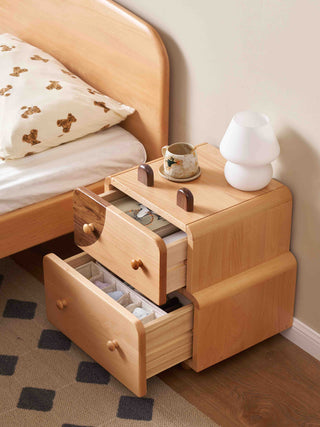 Wooden kids nightstand with open drawers next to a bed